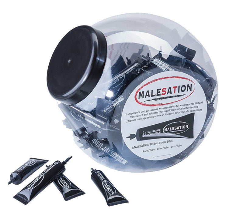 MALESATION Body Lotion – rundes transparentes Verkaufsdisplay mit schwarzem Deckel, weißem MALESATION Markenetikett und mehreren einzeln verpackten Massagelotion-Sachets, drei schwarze Portionsbeutel liegen vor dem Display auf weißem Hintergrund – erhältlich bei Evoria Care