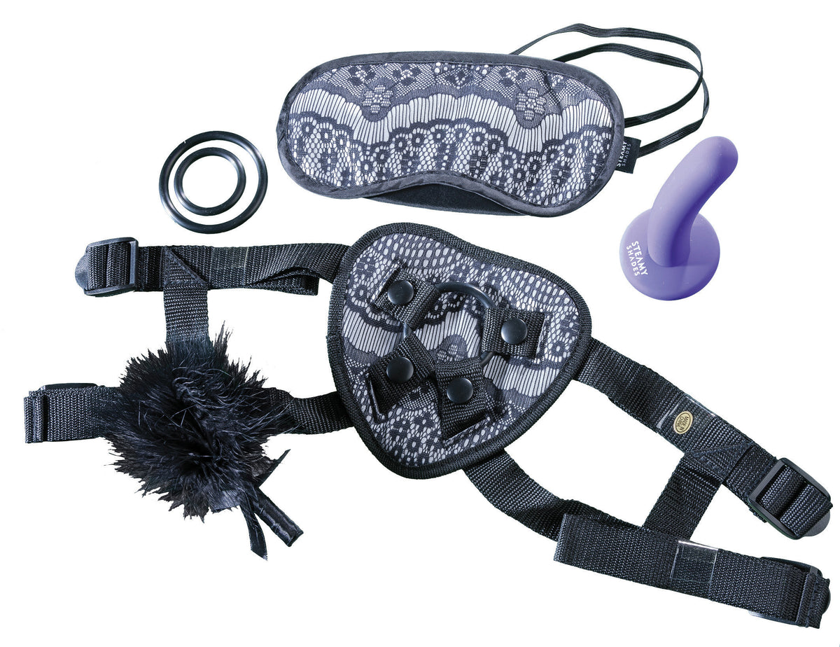 STEAMY SHADES Harness Gift Set mit lilafarbenem Dildo, schwarzem verstellbarem Strap-on Harness, silberfarbenen Metallringen und schwarzer Augenmaske in diagonaler Detailansicht – erhältlich bei Evoria Care