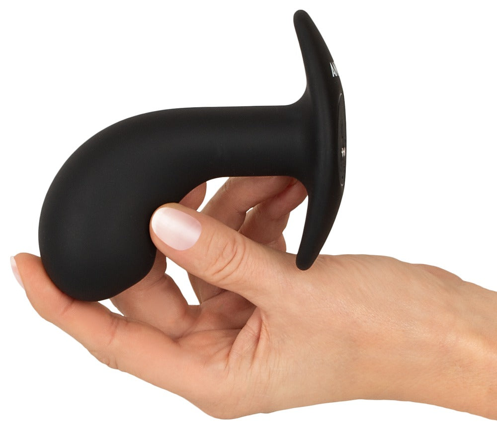 ANOS Big Head Prostate Plug in Schwarz – Größenvergleich in einer Hand zur Darstellung der gebogenen Form und des großen Kopfbereichs