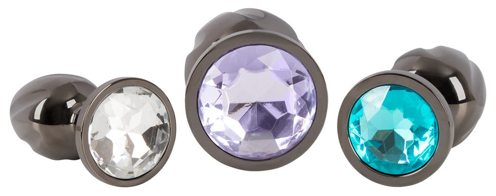 ANOS Metall-Analplug-Set – Detailansicht der runden Basen mit Schmucksteinen in Lila, Klar und Türkis