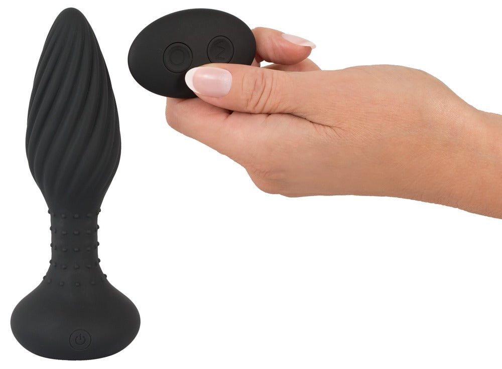 ANOS rotierender Analplug in Schwarz – Größenvergleich in einer Hand mit strukturierter Plugform und breiter Basis