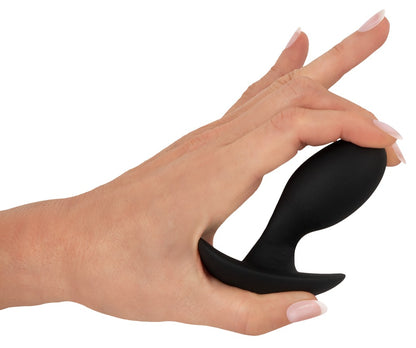 ANOS Vibro-Analplug in Schwarz – Darstellung der flexiblen Form durch seitliches Biegen in einer Hand
