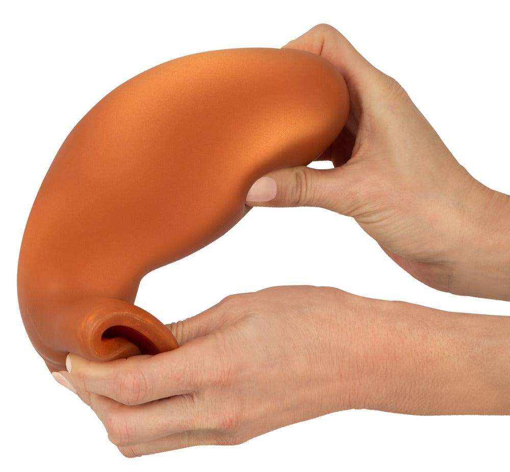 ANOS XL Analplug aus Liquid Silicone in Orange – gebogene Produktansicht zur Darstellung der Flexibilität des Materials