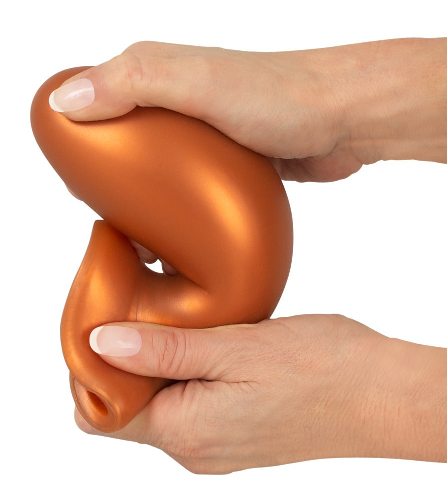 ANOS XL Analplug aus Liquid Silicone in Orange – Größenvergleich in einer Hand zur Darstellung der voluminösen XL-Form