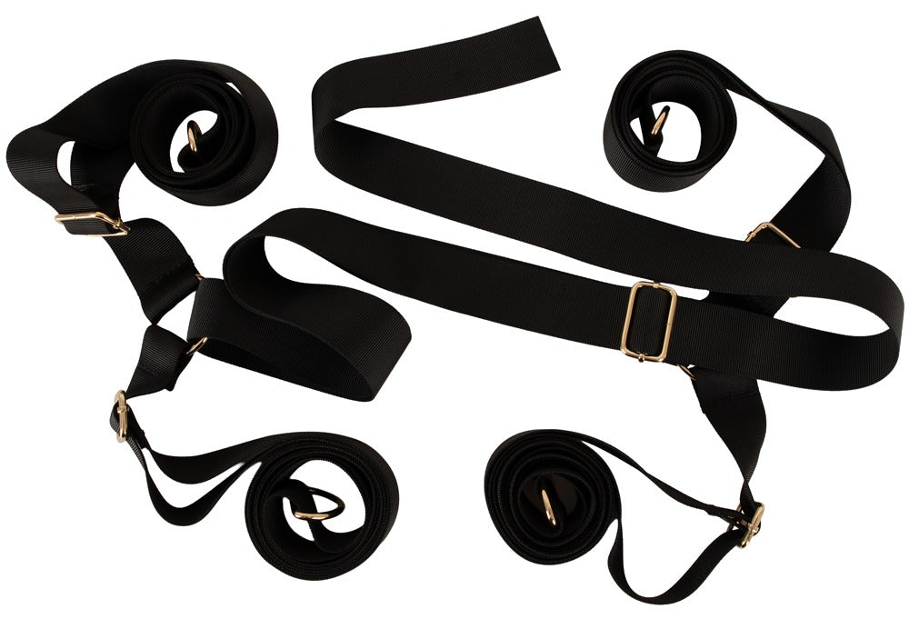 Ausgebreitetes schwarzes Gurtkreuz des Bad Kitty Bettfessel-Sets Deluxe mit Metallringen