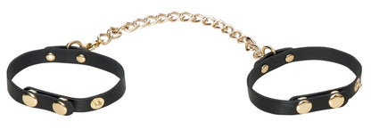 Schwarze Fußfesseln mit goldfarbener Verbindungskette aus dem Bad Kitty Bondage-Set