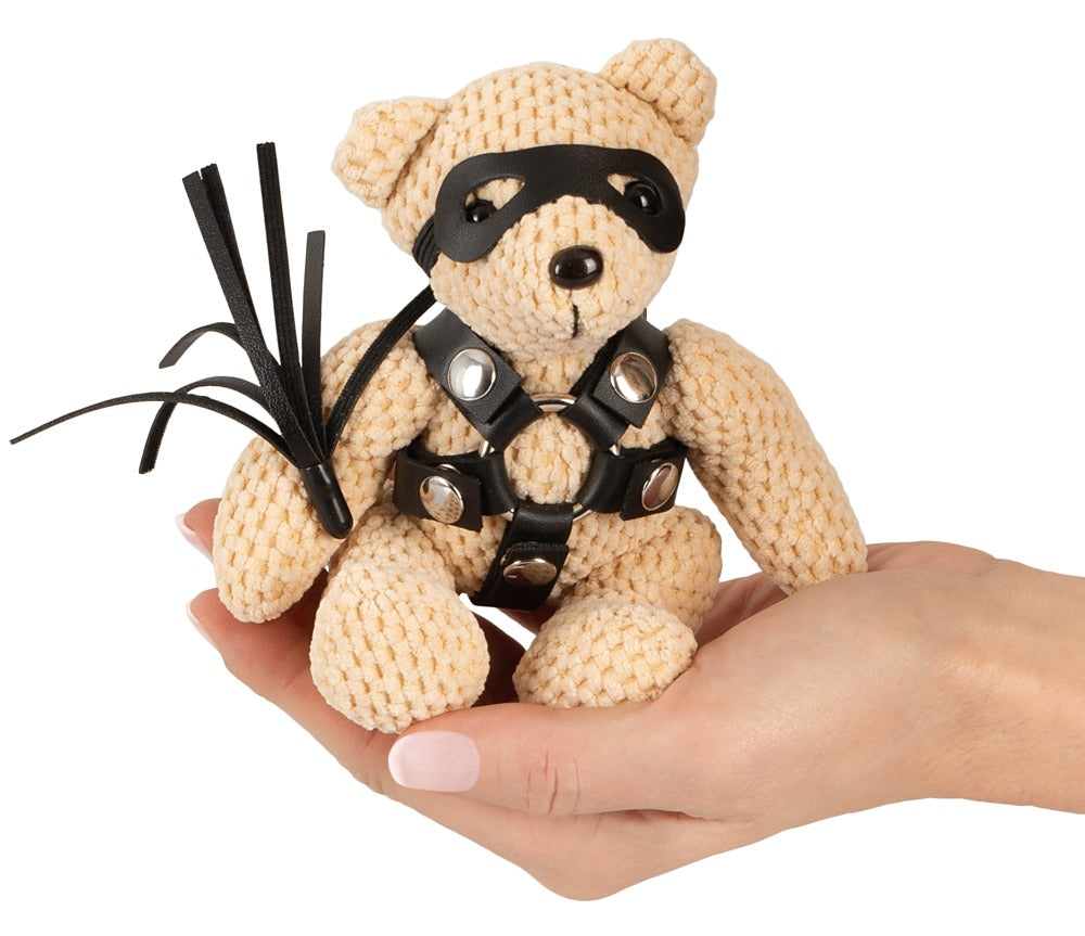 Bad Kitty SM-Teddy Schlüsselanhänger mit schwarzem Harness in einer Hand gehalten