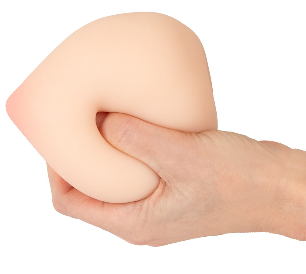 Hand drückt den beau cœur FELYRA Peach Masturbator und zeigt die weiche flexible Nature Skin TPE-Oberfläche