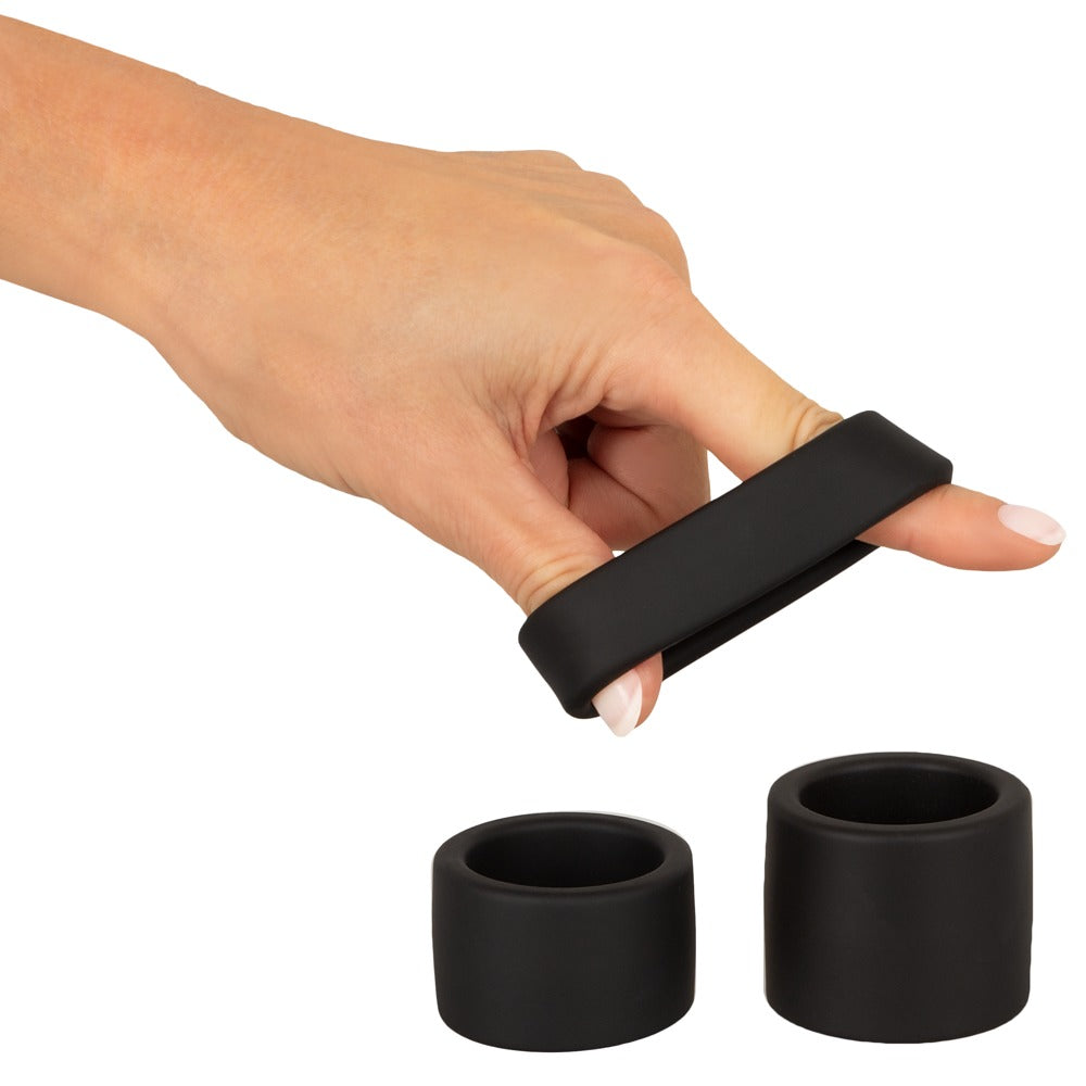 Erecto Ball Stretcher Ring bei der Dehnungsdemonstration zwischen zwei Händen mit weiteren Ringen daneben