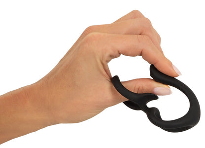 Erecto Cock & Ball Ring bei der Dehnungsdemonstration in der Hand mit elastischen verbundenen Ringen