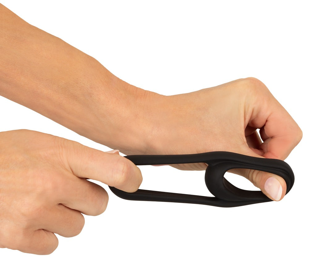 Erecto Cock & Ball Ring bei der Dehnungsdemonstration zwischen zwei Händen mit elastischer Ringkonstruktion
