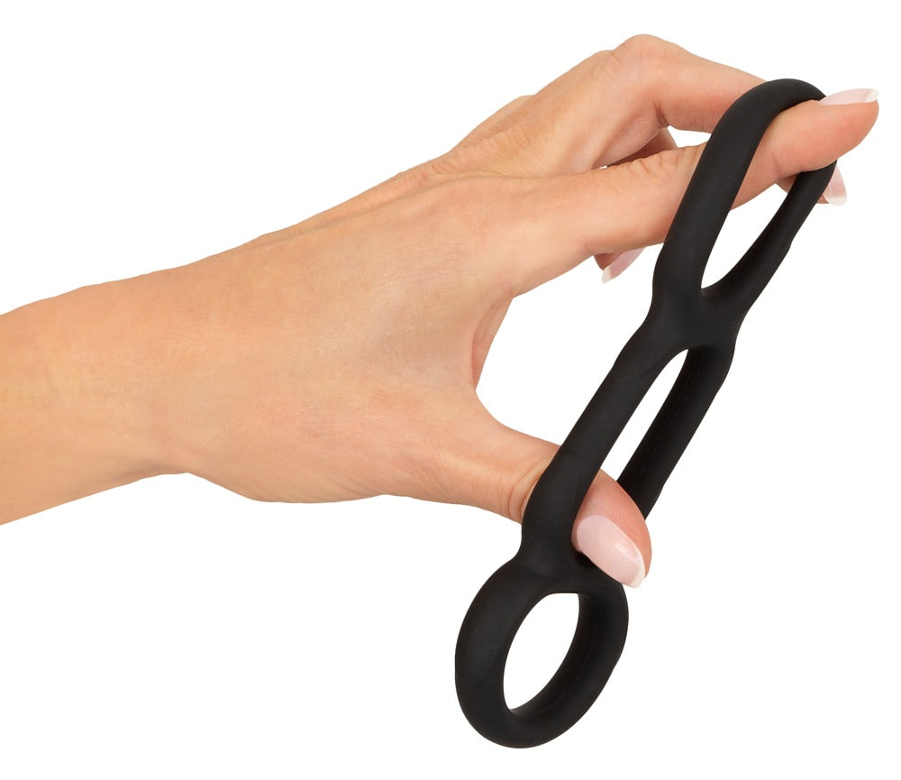 Erecto Triple Cock Ring bei der Dehnungsdemonstration in der Hand mit elastischen verbundenen Silikonringen