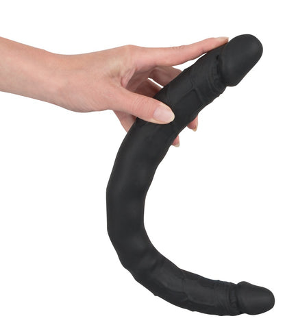 Bad Kitty Double Dong schwarzer flexibler Doppeldildo mit zwei Enden, von einer Hand gehalten und U-förmig gebogen zur Veranschaulichung der Biegsamkeit – erhältlich bei Evoria Care