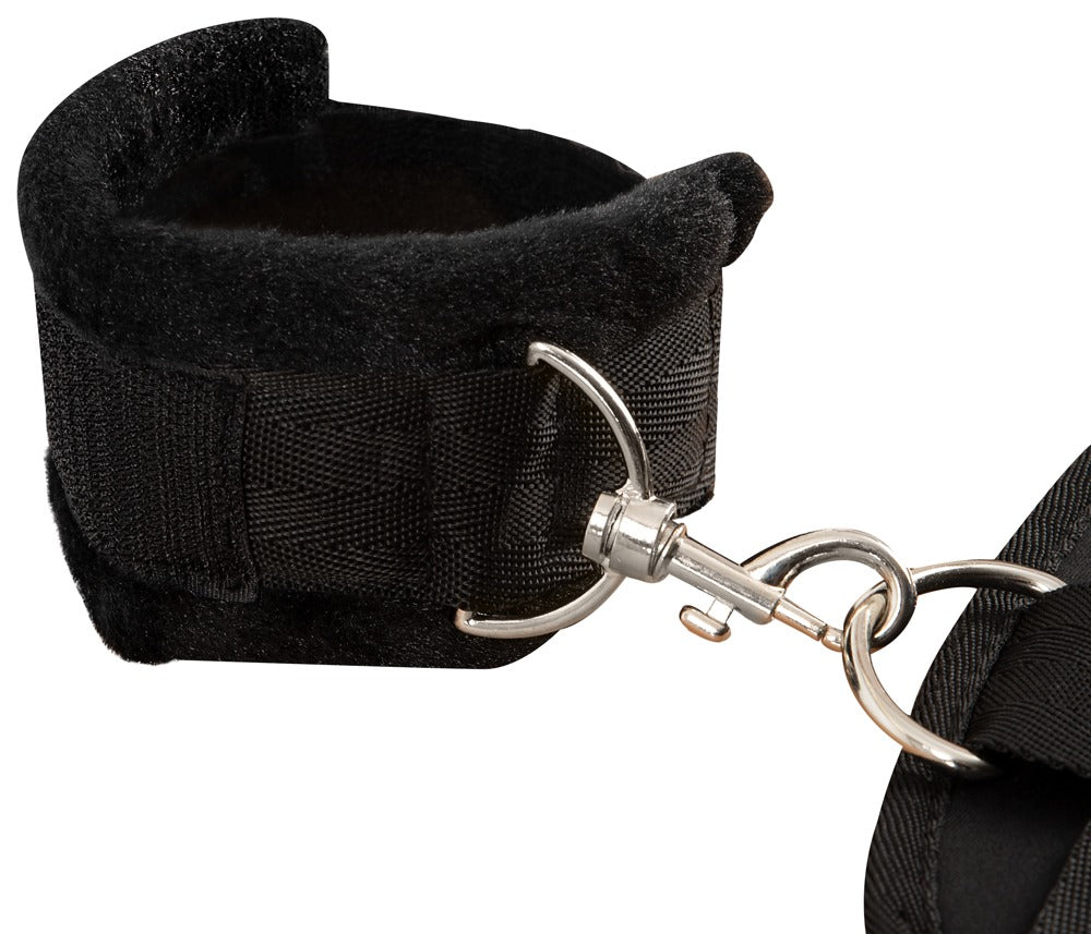 Bad Kitty Ganzkörper-Bondage-Set schwarze gepolsterte Fesselmanschette mit breitem Riemen, verstellbarem Verschluss und silberfarbenem Verbindungselement in seitlicher Nahaufnahme – erhältlich bei Evoria Care