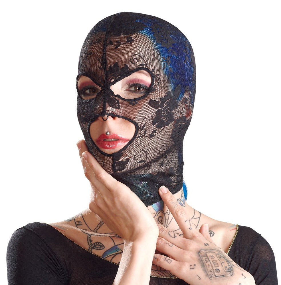 Bad Kitty Kopfmaske in Schwarz aus weicher elastischer Spitze mit floralem Muster und eingefassten Gesichtsöffnungen, am Model in leicht seitlich gedrehter Porträtansicht mit Hand am Gesicht – erhältlich bei Evoria Care