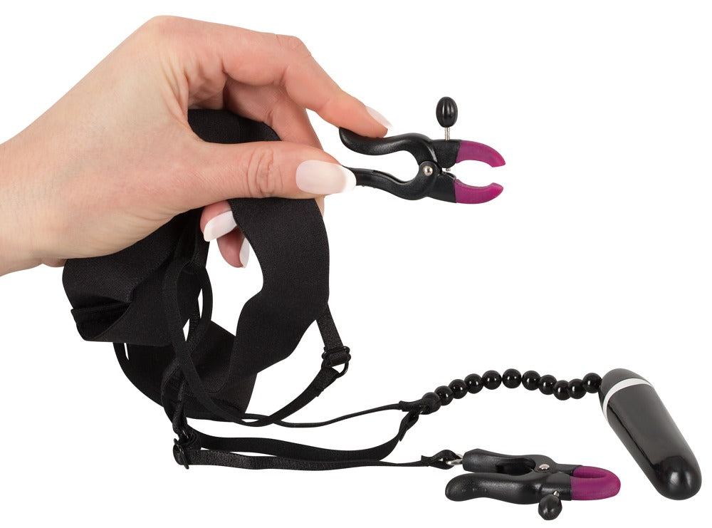 Bad Kitty Spreader String mit Vibrator und Vulvaklemmen, Detailansicht des schwarz-silberfarbenen Zubehörs bei der Handhabung sowie weiterer Set-Bestandteile – erhältlich bei Evoria Care