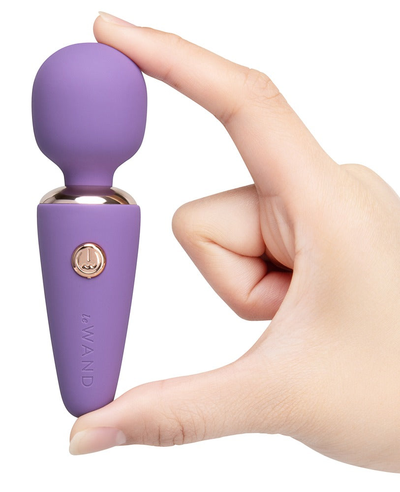 le WAND Mini Microwand in Lila mit goldfarbenen Bedientasten, aufrecht in einer Hand gehalten zur Darstellung von Größe und Handhabung – erhältlich bei Evoria Care