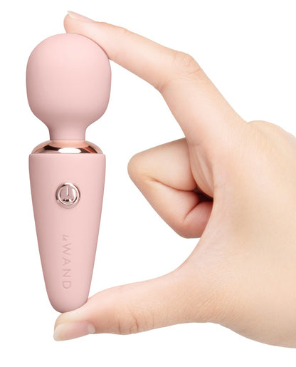 le WAND Mini Microwand in Rosa mit roségoldfarbenen Bedientasten, aufrecht in einer Hand gehalten zur Darstellung von Größe und Handhabung – erhältlich bei Evoria Care