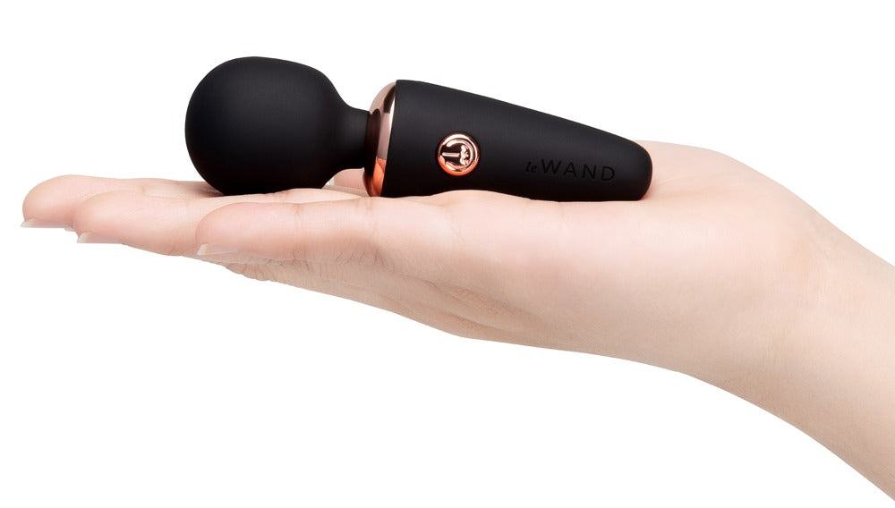 le WAND Mini Microwand schwarzer Mini-Massagestab auf einer ausgestreckten Hand zur Veranschaulichung seiner kompakten Größe – erhältlich bei Evoria Care