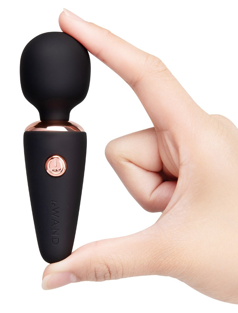 le WAND Mini Microwand in Schwarz mit roségoldfarbenen Bedientasten, aufrecht in einer Hand gehalten zur Darstellung der Handhabung – erhältlich bei Evoria Care