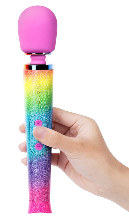 le WAND Petite All That Glimmers Massagestab mit buntem Glitzerdesign, aufrecht in einer Hand gehalten zur Veranschaulichung von Größe und Handhabung – erhältlich bei Evoria Care