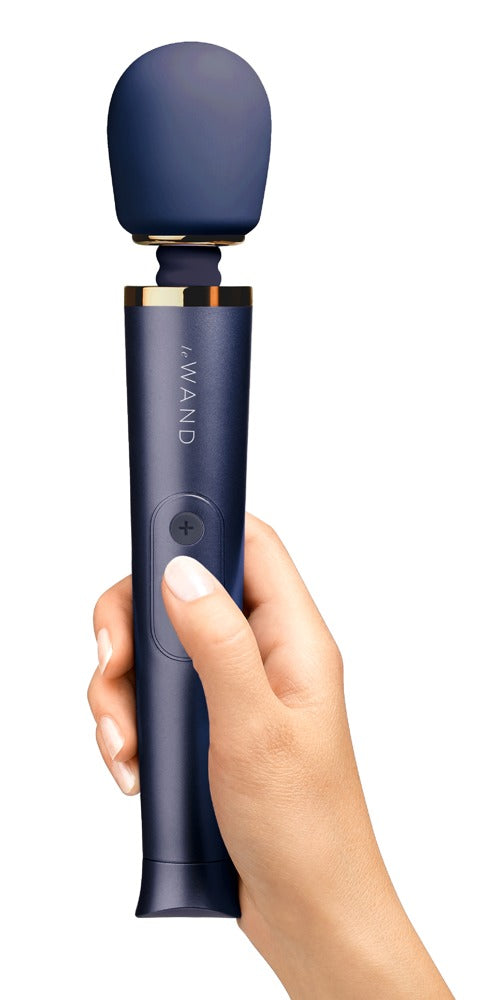 le WAND Petite Wand Massager in Dunkelblau mit goldfarbenen Akzenten, aufrecht in einer Hand gehalten zur Veranschaulichung von Größe und Handhabung – erhältlich bei Evoria Care
