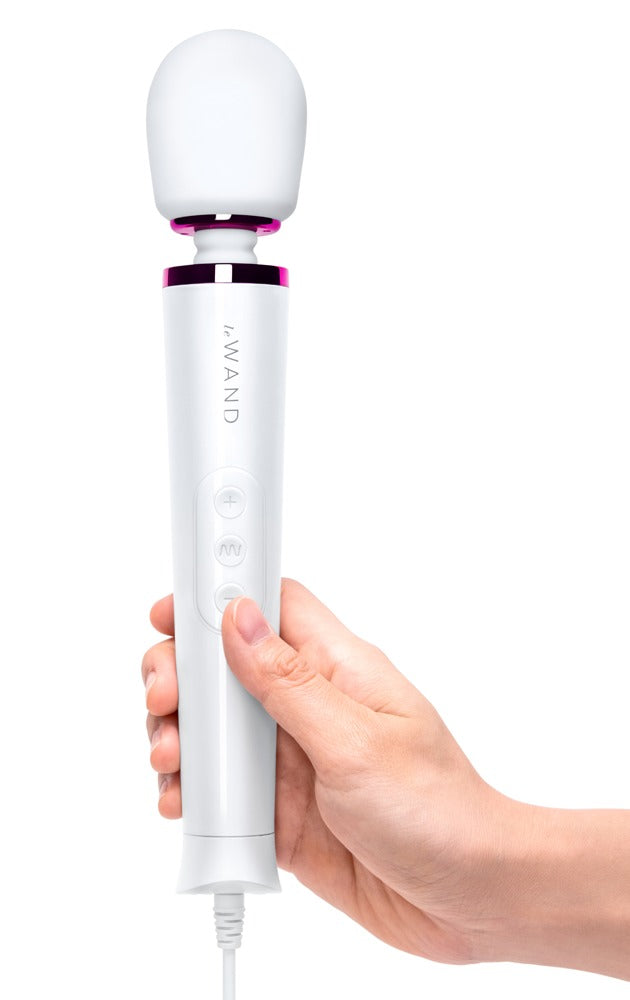 le WAND Powerful Petite weißer Massagestab mit pinkfarbenem Zierring, aufrecht in einer Hand gehalten zur Veranschaulichung von Größe und Handhabung – erhältlich bei Evoria Care