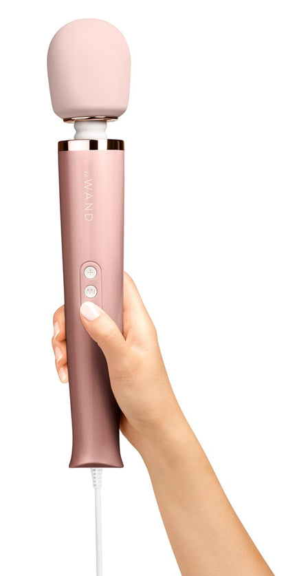 le WAND Powerful Plug-In Massagestab in Roségold mit rosafarbenem Massagekopf, aufrecht in einer Hand gehalten zur Veranschaulichung von Größe und Handhabung – erhältlich bei Evoria Care