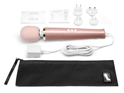 le WAND Powerful Plug-In Luxus-Massagestab in Roségold mit verschiedenen Massageaufsätzen, Anschlusskabel und schwarzem Aufbewahrungszubehör in einer Produktübersicht – erhältlich bei Evoria Care