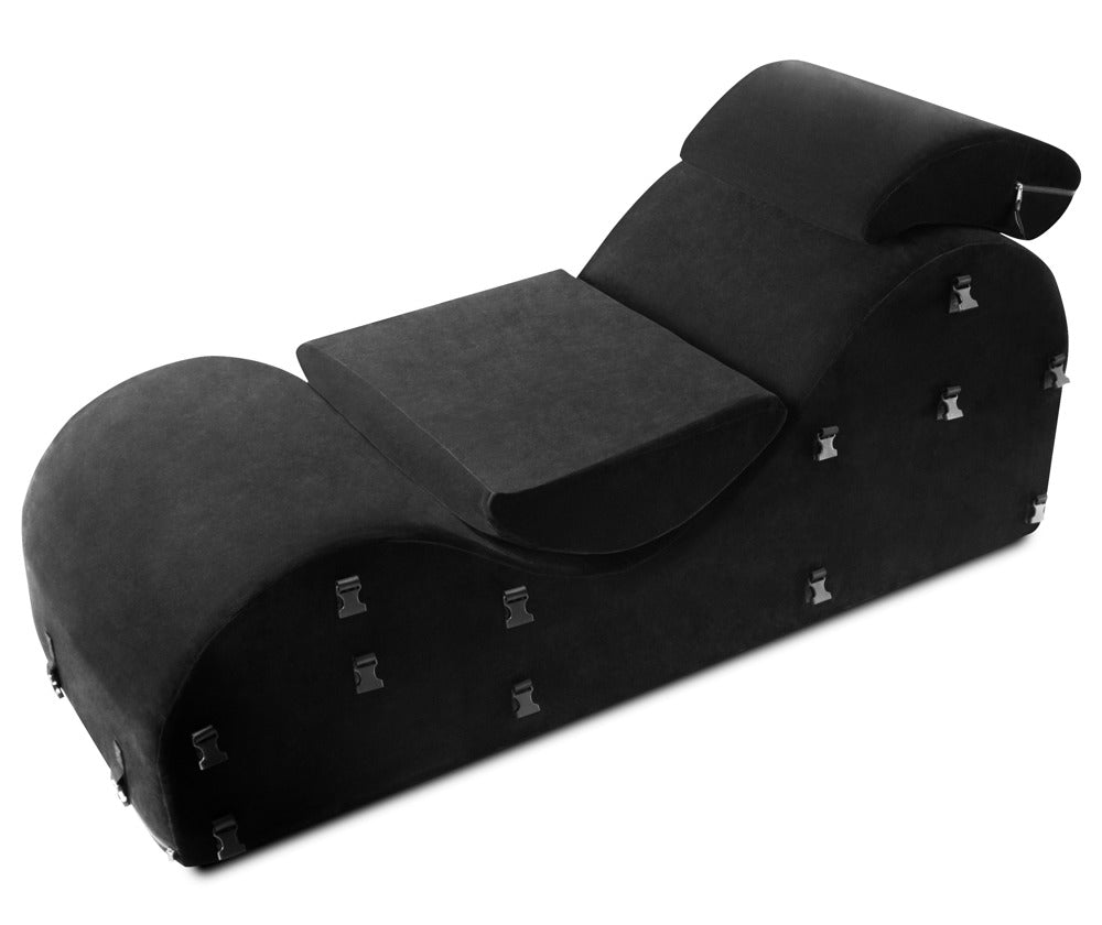 Liberator Black Label Esse – schwarze Premium-Bondage-Lounge mit geschwungener Polsterform, integrierten Fixiergurten, Metallringen und zusätzlichen Stützkissen in schräger Draufsicht auf weißem Hintergrund – erhältlich bei Evoria Care