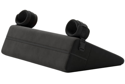 Liberator Bondage Wedge – schwarzes keilförmiges Bondage-Liebeskissen mit zwei gepolsterten Soft-Fesseln an der erhöhten Kissenseite und seitlich sichtbarem Liberator Markenetikett auf weißem Hintergrund – erhältlich bei Evoria Care