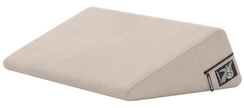Liberator Wedge – beigefarbenes ergonomisches Sexkissen mit keilförmiger Polsterung, glatter Liegefläche, flach zulaufender Vorderkante und seitlichem Liberator Markenetikett in schräger Produktansicht auf weißem Hintergrund – erhältlich bei Evoria Care