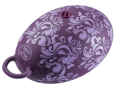 MINDS of LOVE Riding Ball Vibratorkissen in Lila mit drei Motoren, Nahaufnahme der gewölbten, dekorativ strukturierten Oberfläche und seitlichen Halteschlaufen in schräger Draufsicht – erhältlich bei Evoria Care