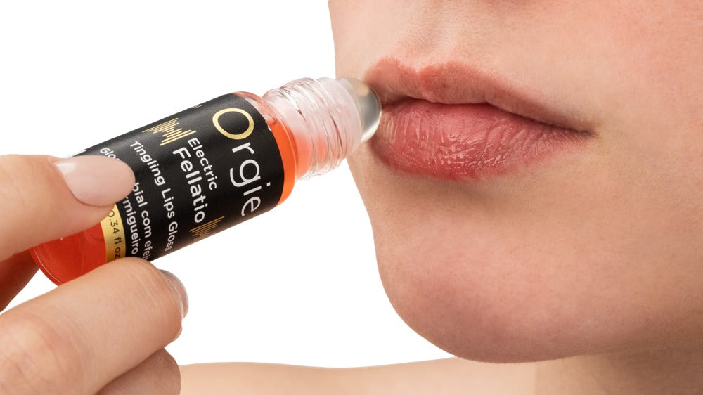 Orgie Electric Fellatio prickelnder Lipgloss mit geöffnetem Fläschchen und Applikator, in einer Hand vor den Lippen gehalten zur Veranschaulichung der Anwendung – erhältlich bei Evoria Care