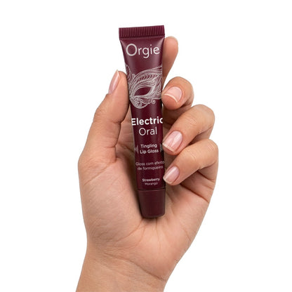 Orgie Electric Oral Tingling Lip Gloss in dunkelroter Tube, aufrecht zwischen den Fingern gehalten zur Veranschaulichung von Größe und Handhabung – erhältlich bei Evoria Care