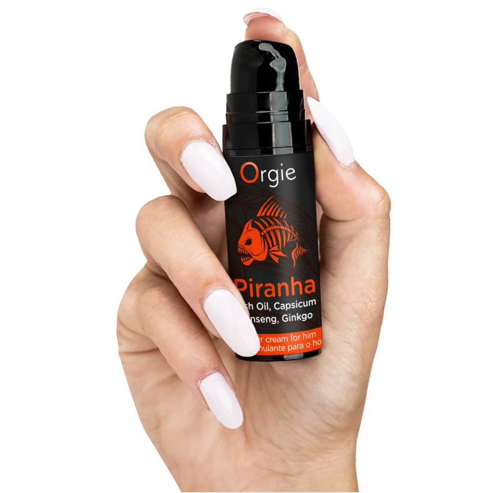 Orgie Piranha Power Cream Stimulationscreme in schwarzer Flasche mit orangefarbenem Etikett, aufrecht in einer Hand gehalten zur Veranschaulichung von Größe und Handhabung – erhältlich bei Evoria Care