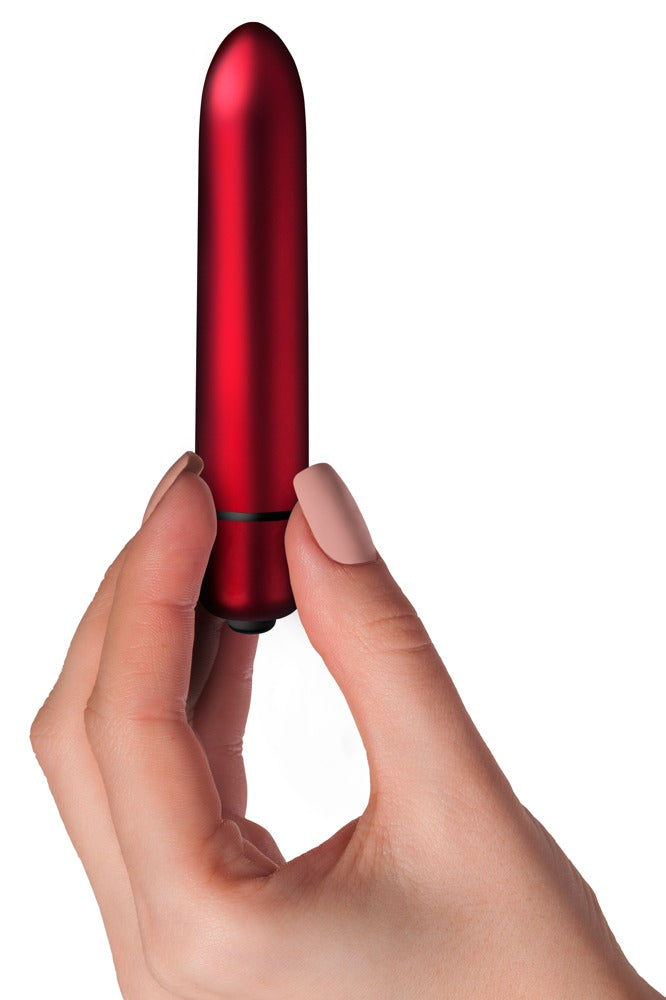 Rocks Off Scarlet Velvet Bullet-Vibrator in Rot und Schwarz – Produkt in einer Hand zur Darstellung der kompakten Größe und schlanken Form – erhältlich bei Evoria Care
