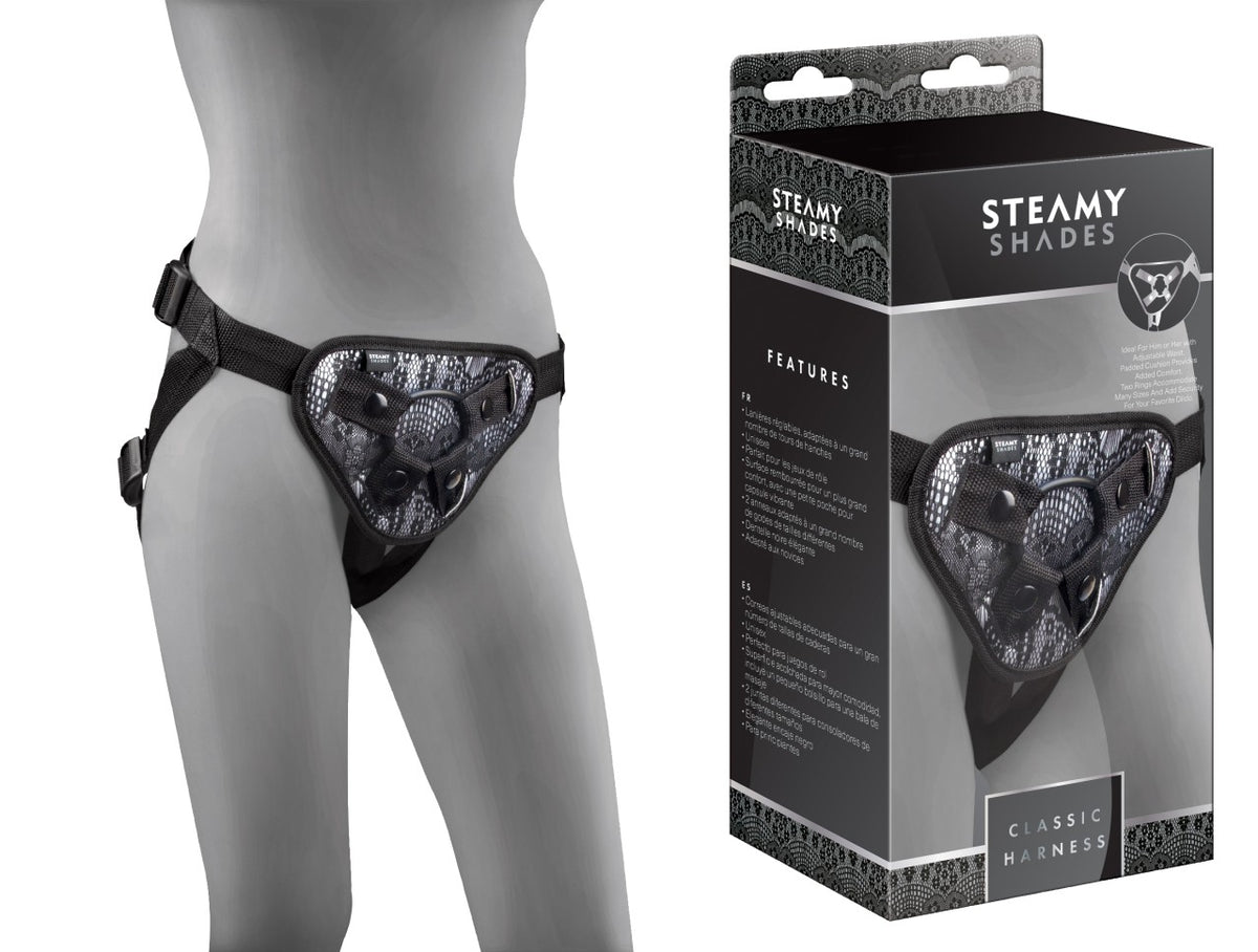 STEAMY SHADES Classic Harness verstellbarer Strap-on Harness in Schwarz mit gemusterter Frontpartie, verstellbaren Hüft- und Schrittgurten sowie zentralem Befestigungsring, an einer grauen Schaufensterpuppe neben der Originalverpackung dargestellt – erhältlich bei Evoria Care