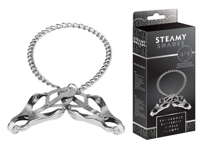 STEAMY SHADES Endurance Butterfly Nipple Clamps mit zwei silberfarbenen schmetterlingsförmigen Brustwarzenklemmen und langer Metallkette, dekorativ geschwungen neben der schwarzen Originalverpackung dargestellt – erhältlich bei Evoria Care