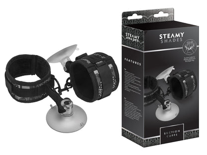 STEAMY SHADES Suction Cuffs gepolsterte Fesseln in Schwarz mit zwei verstellbaren Manschetten, silberfarbenen Verbindungselementen und transparenten Saugnäpfen, dargestellt neben der schwarzen Originalverpackung – erhältlich bei Evoria Care