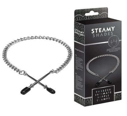 STEAMY SHADES Tweezer Intimate Nipple Clamps mit zwei silberfarbenen Pinzetten-Nippelklemmen, schwarzen Schutzkappen und langer Metallkette, dekorativ in Herzform angeordnet neben der schwarzen Originalverpackung – erhältlich bei Evoria Care