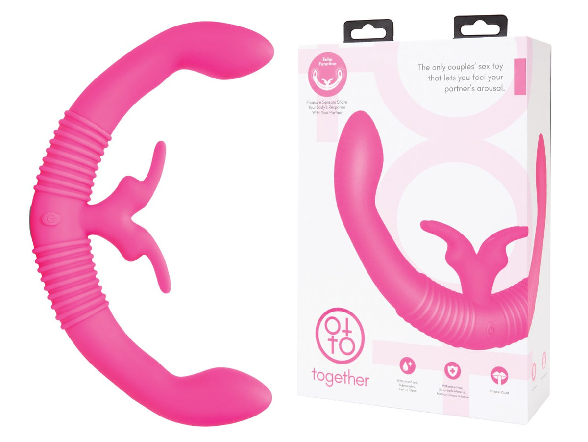 TogetherVibes Together – pinkfarbener Paarvibrator mit flexibler U-förmiger Konstruktion, zwei abgerundeten Stimulationsenden, strukturiertem Schaft und Echo-Funktion neben der weiß-rosa Originalverpackung – erhältlich bei Evoria Care