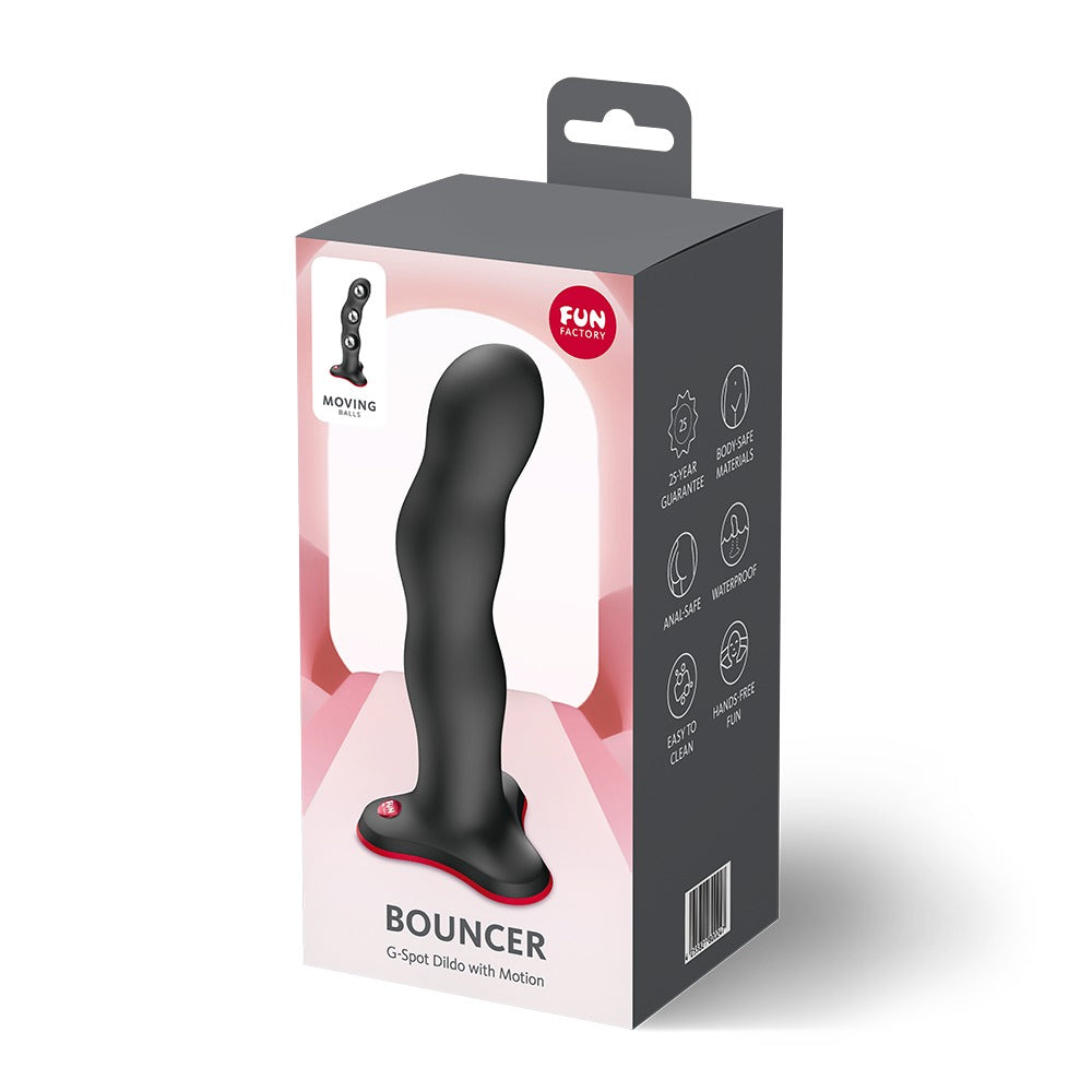 FUN FACTORY BOUNCER Dildo in Schwarz mit rotem Saugfuß neben der Originalverpackung
