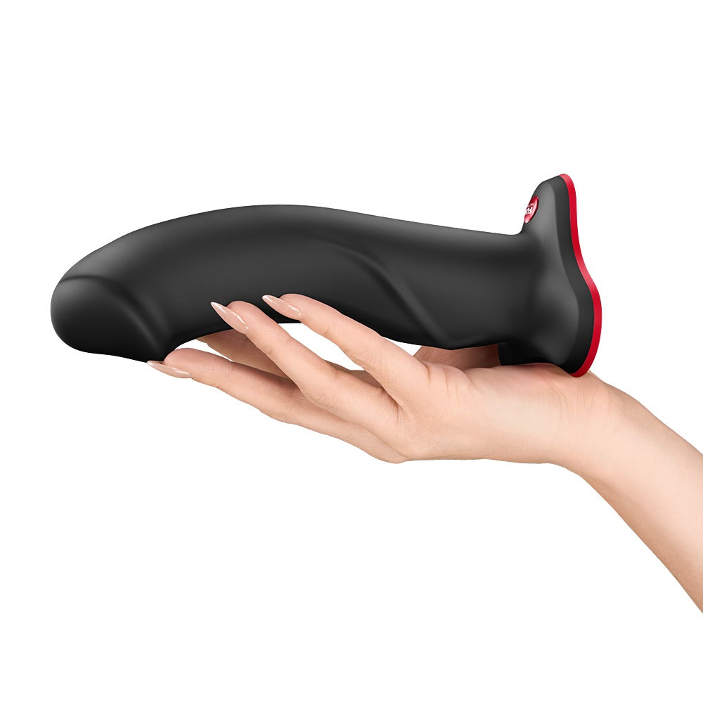 FUN FACTORY THE BOSS STUB realistischer Dildo in Schwarz mit Saugfuß auf einer Hand zur Veranschaulichung der Produktgröße