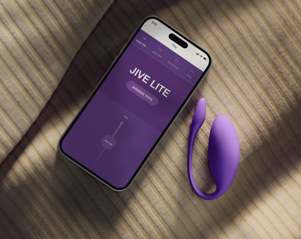 We-Vibe Jive Lite Vibro-Ei in Lila neben einem Smartphone mit geöffneter App