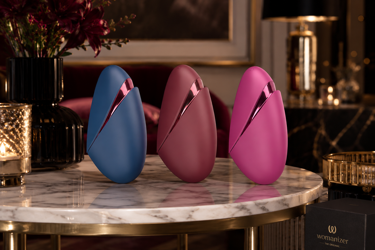 Womanizer Next Liberty in Blau, Rot und Pink auf einem luxuriösen Marmortisch in exklusiver Premium-Umgebung präsentiert.