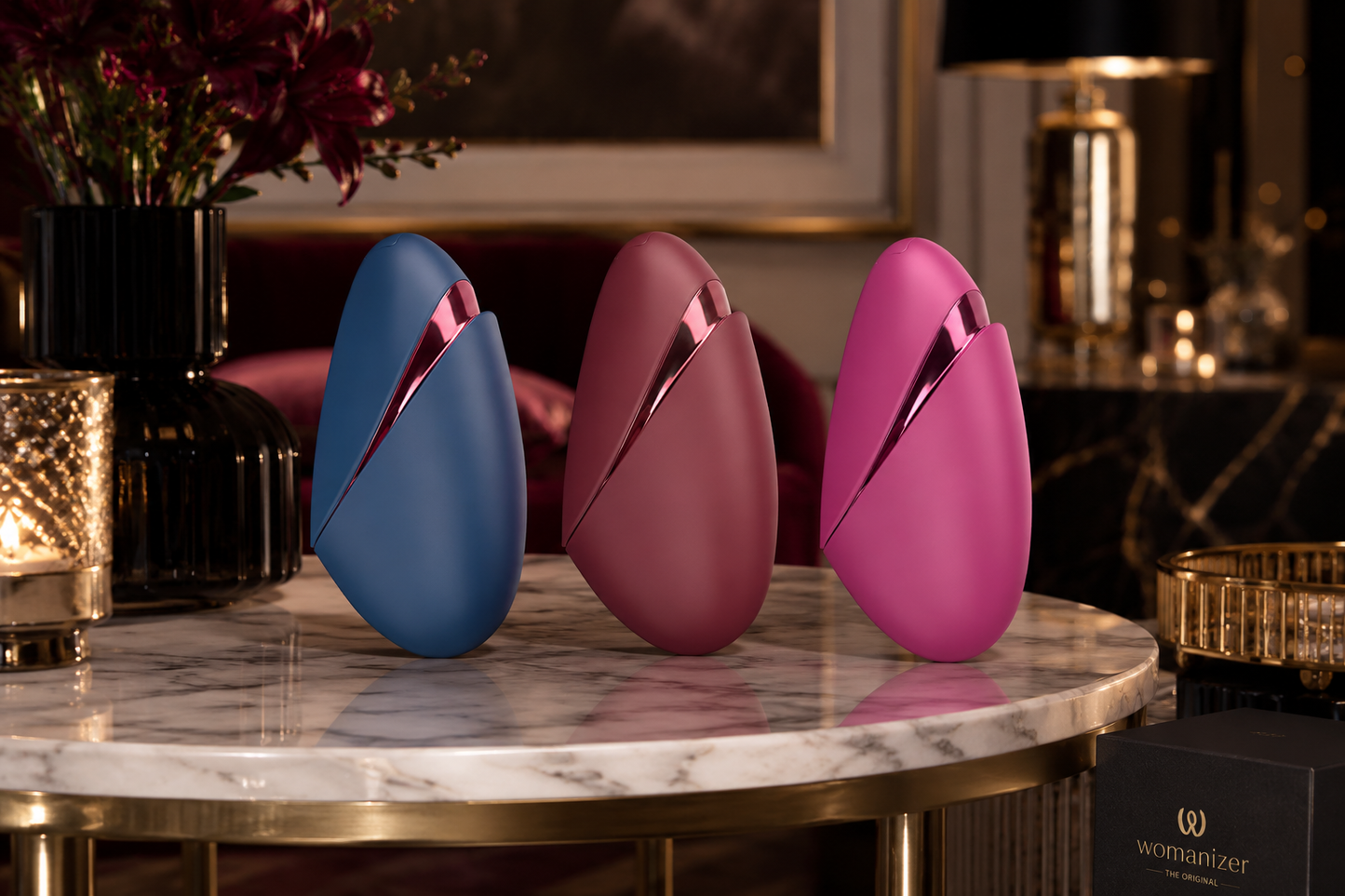 Womanizer Next Liberty in Blau, Rot und Pink auf einem luxuriösen Marmortisch in exklusiver Premium-Umgebung präsentiert.