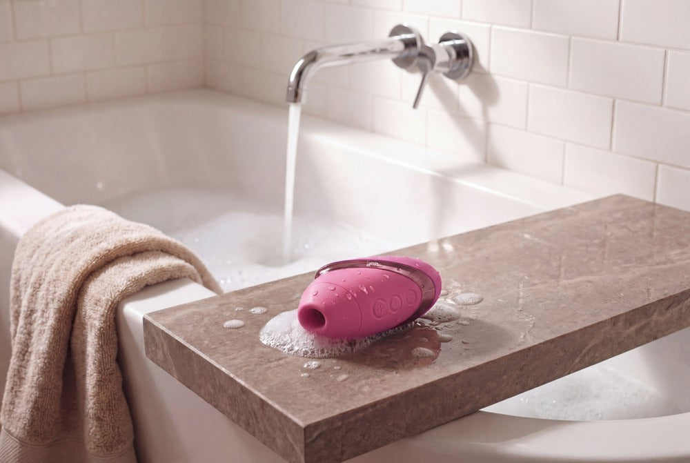 Womanizer Next Liberty in Pink auf einem Nachttisch im Lifestyle-Motiv