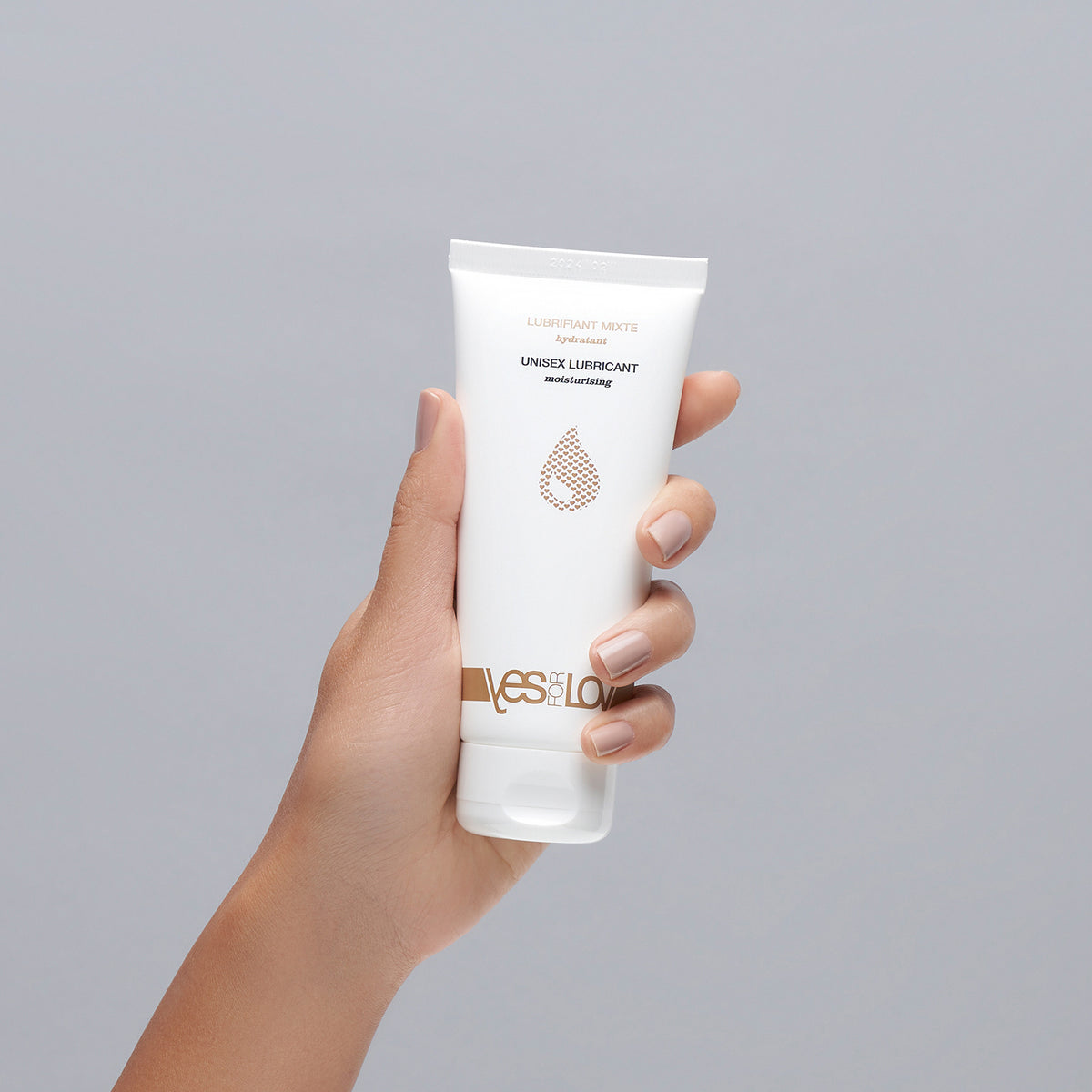 YESforLOV Natural Intimate Lubricant in weißer Tube in einer Hand vor neutralem Hintergrund
