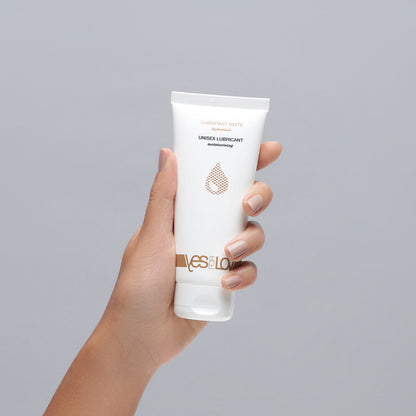 YESforLOV Natural Intimate Lubricant in weißer Tube in einer Hand vor neutralem Hintergrund